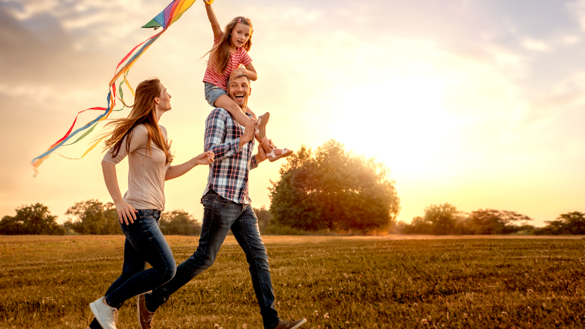 family running through field letting kite fly